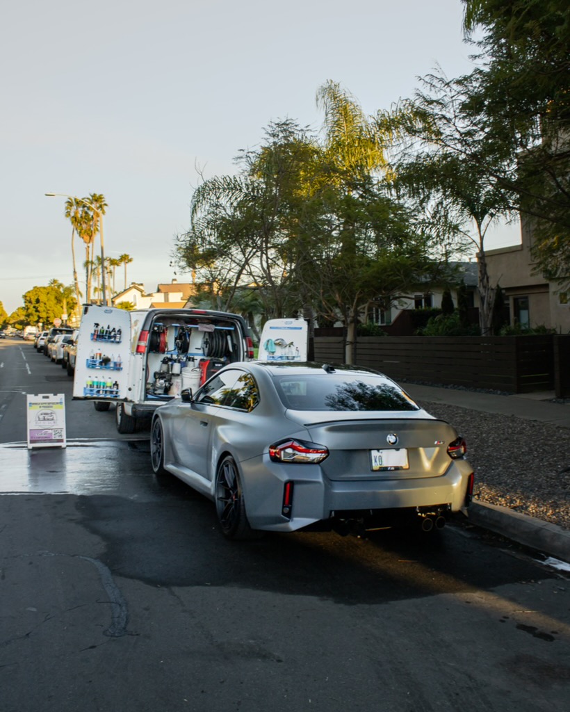 Silver BMW M2 alongside the mobile detailing vans
